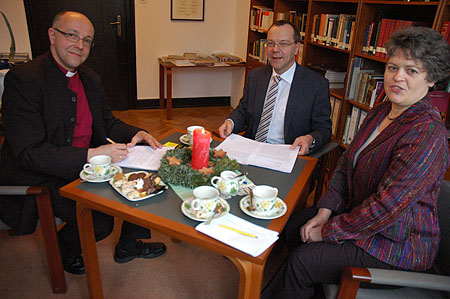Bischof Hans-Jörg Voigt, Geschäftsführender Kirchenrat Michael Schätzel und Verlegerin Dr. Reinhilde Ruprecht bei der Unterzeichnung der Vertragsexemplare
